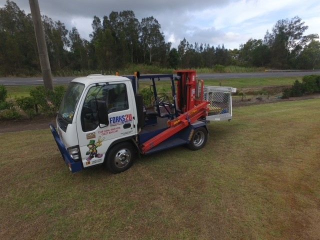 A Tow Truck With a Crane Attached to the Back is Parked in a Grassy Field — O'Grady's Transport & Removals in Lismore, NSW