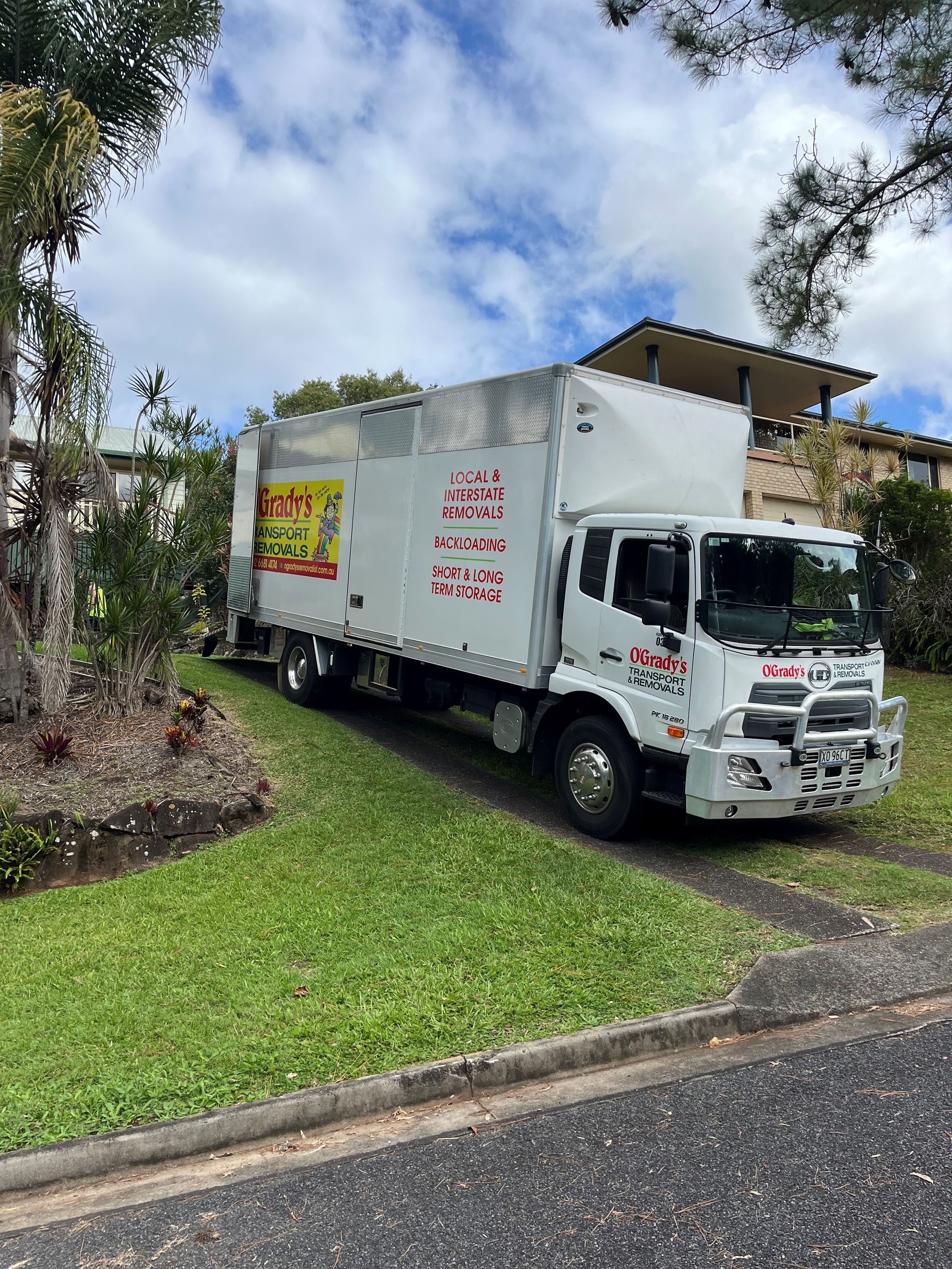 A White Truck is Parked on the Side of the Road in Front of a House — O'Grady's Transport & Removals in Port Stephens, NSW