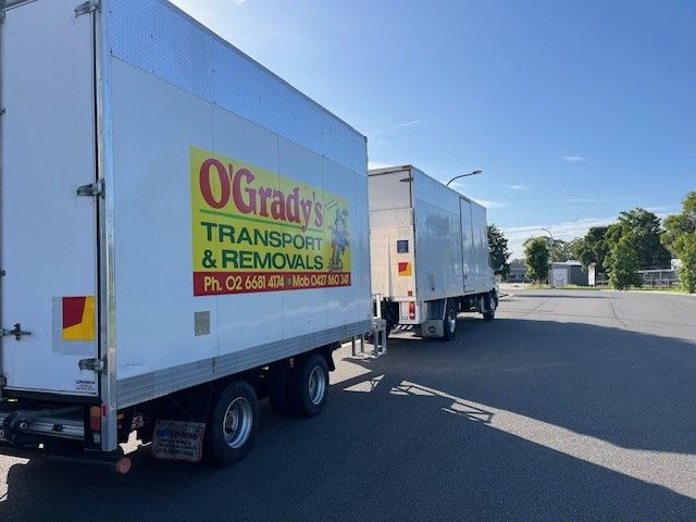 A Family is Sitting on a Couch in a Living Room Looking at a Cell Phone — O'Grady's Transport & Removals in Alstonville, NSW