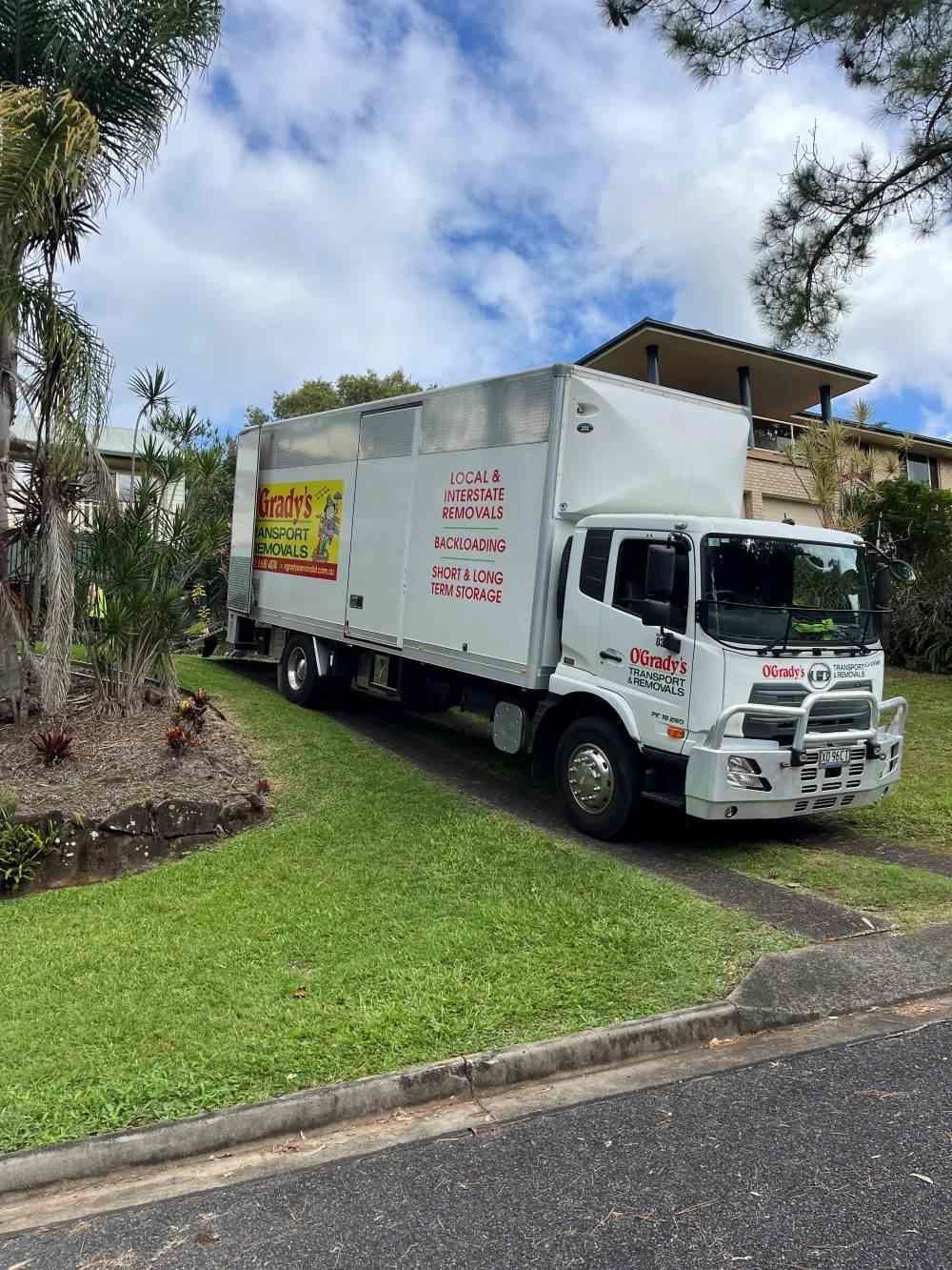 A White Truck Is Parked on The Side of The Road in Front of A House — O'Grady's Transport & Removals in Alstonville, NSW