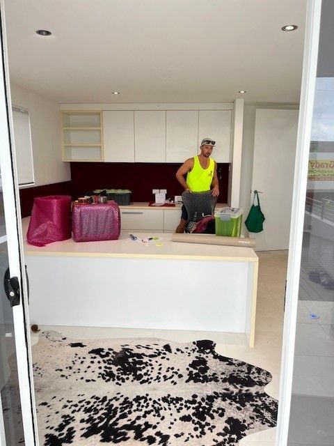 A Man in a Yellow Tank Top is Standing in a Kitchen — O'Grady's Transport & Removals in Forster, NSW