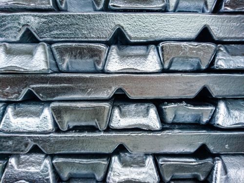 Stacked silver metal bars with rough, reflective surfaces