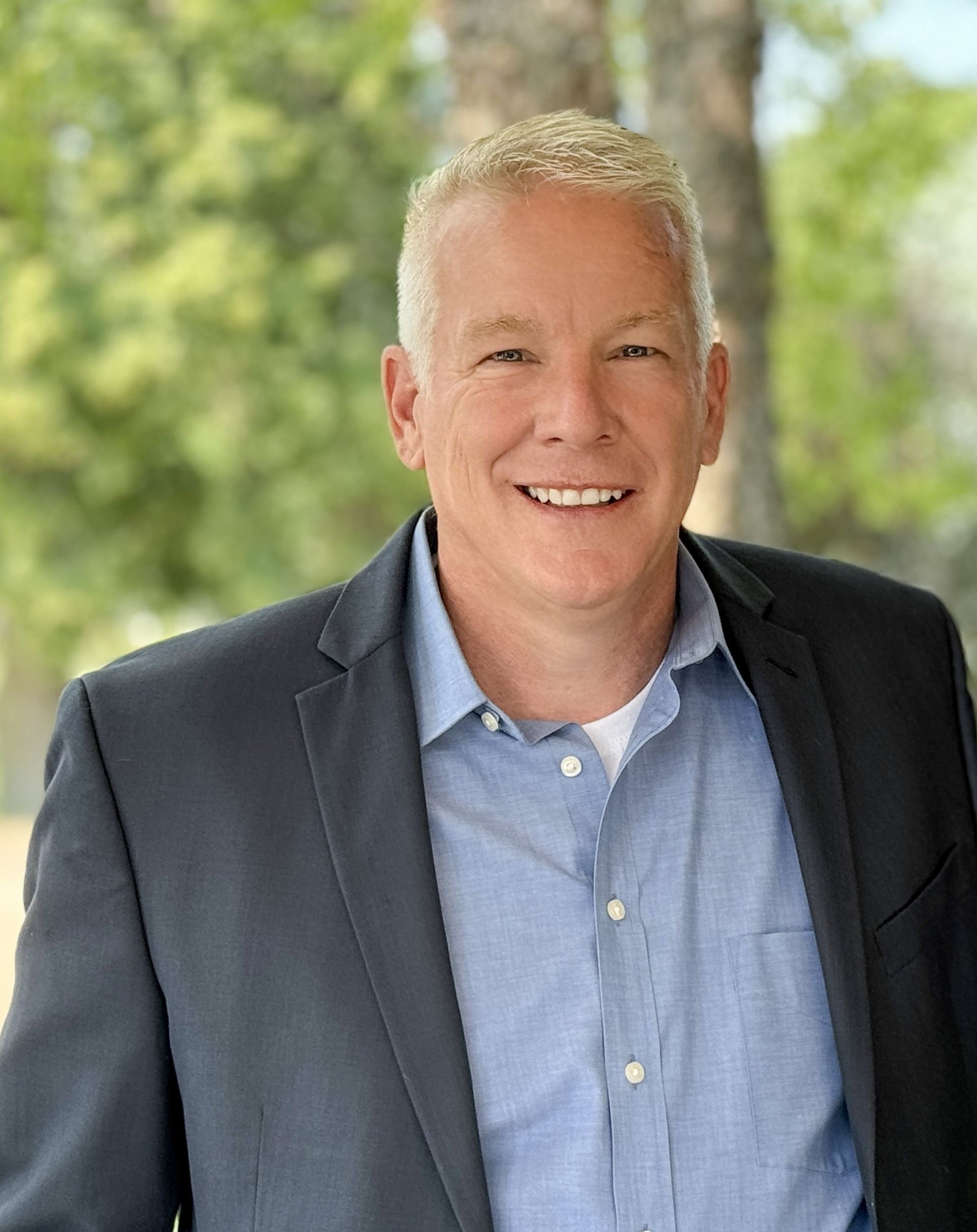 A man in a suit and blue shirt is smiling for the camera.