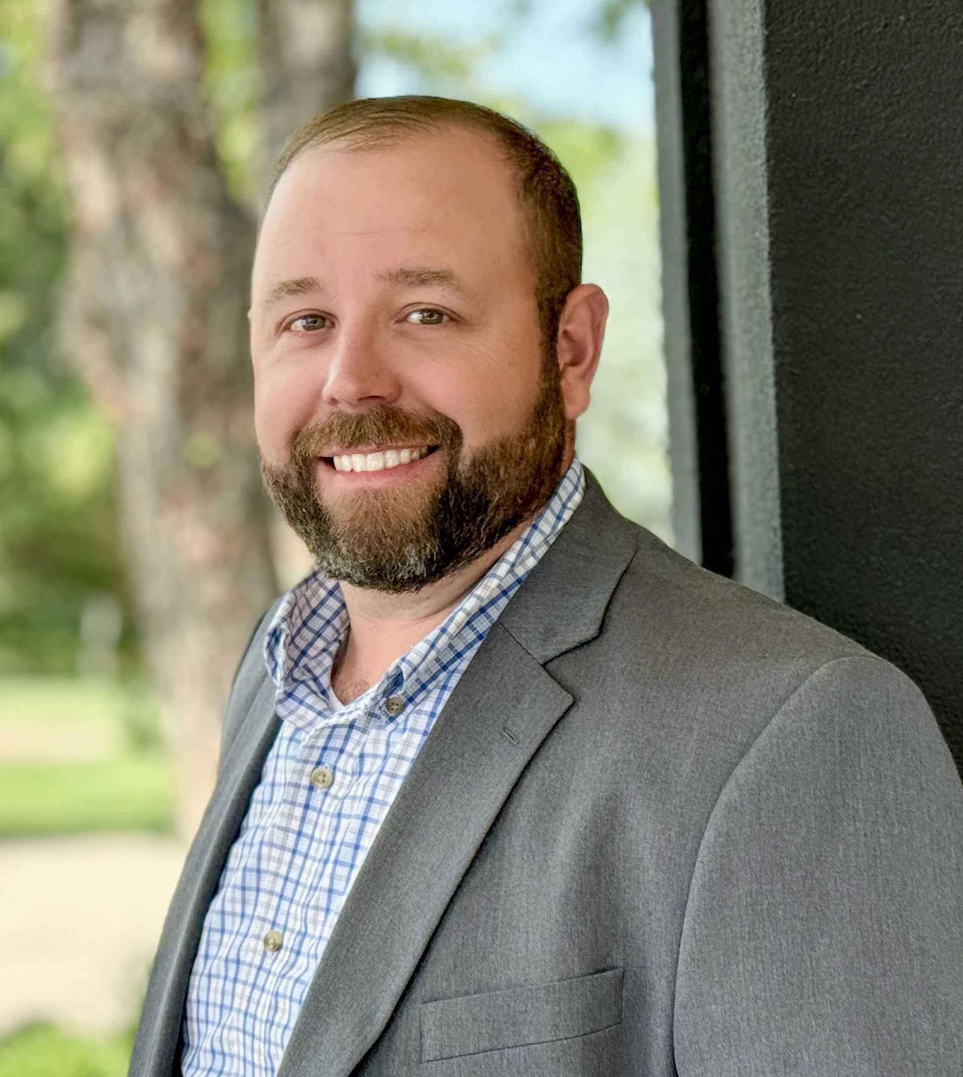 A man with a beard is wearing a suit and smiling for the camera.