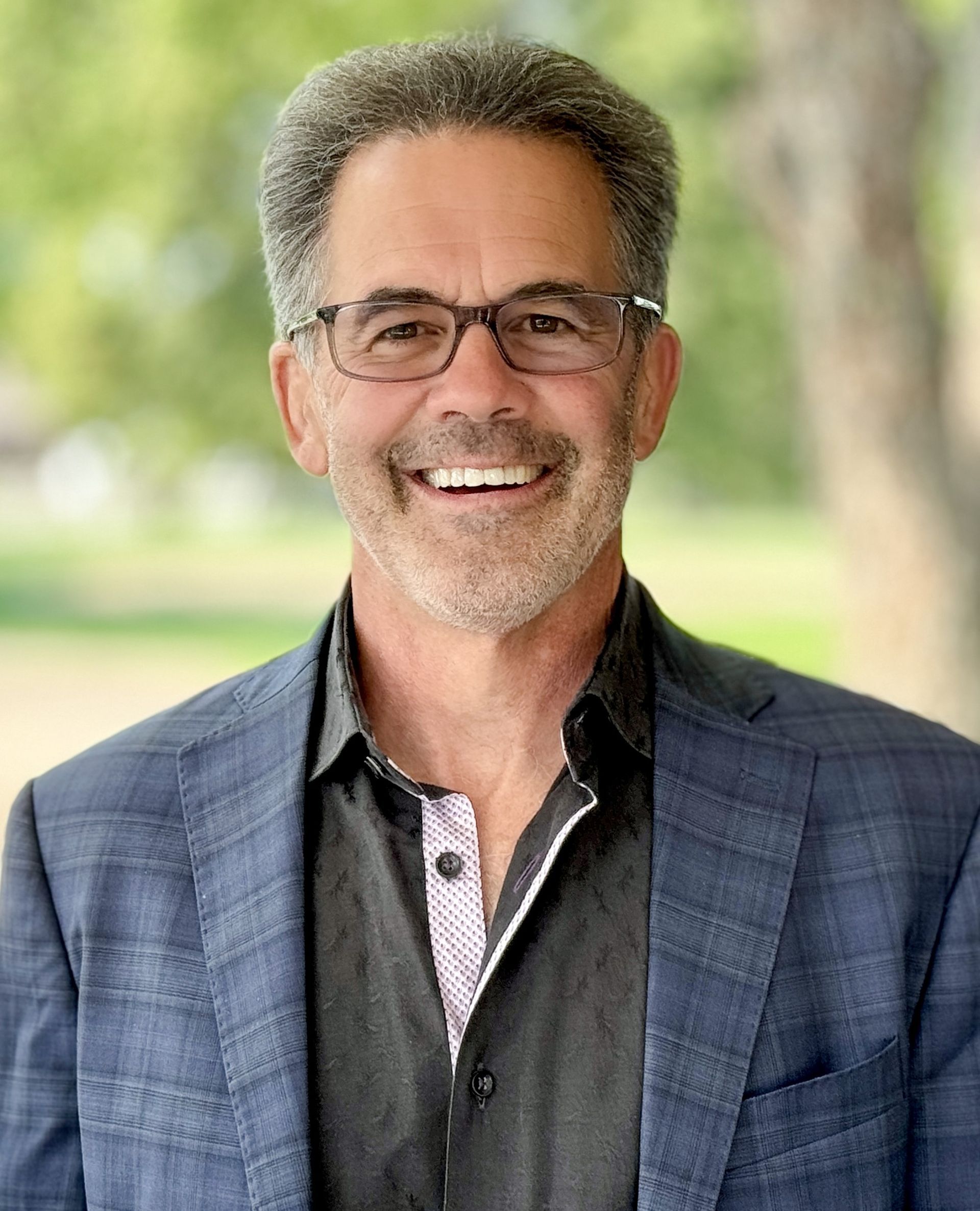 A man in a suit and glasses is smiling for the camera.