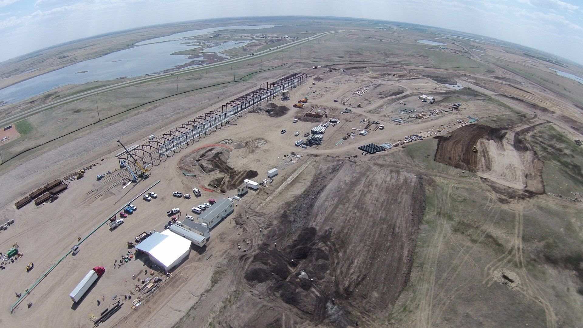 An aerial view of a large dirt field with a lot of trucks parked in it.