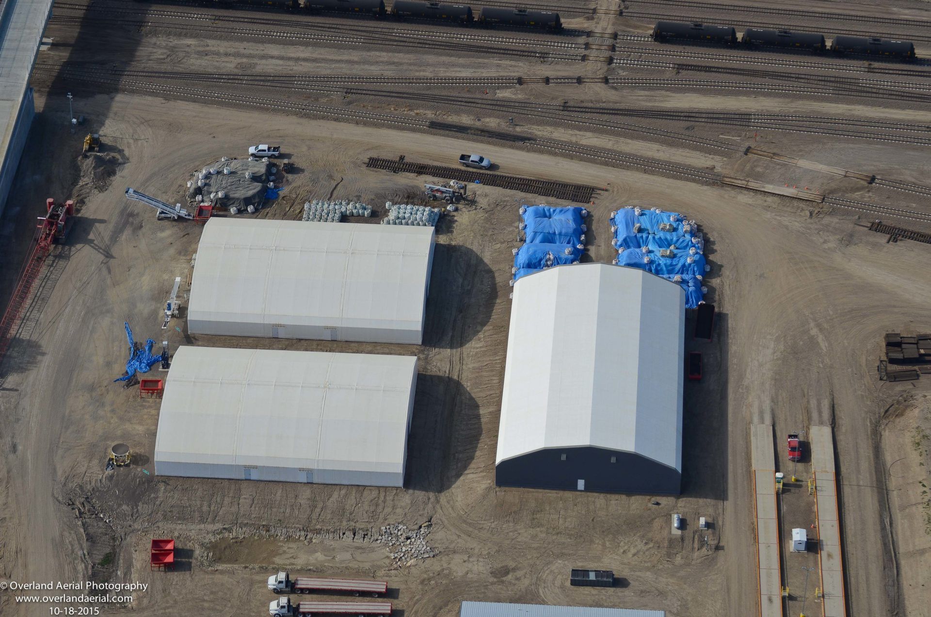 An aerial view of a warehouse with a lot of blue tarps on the ground