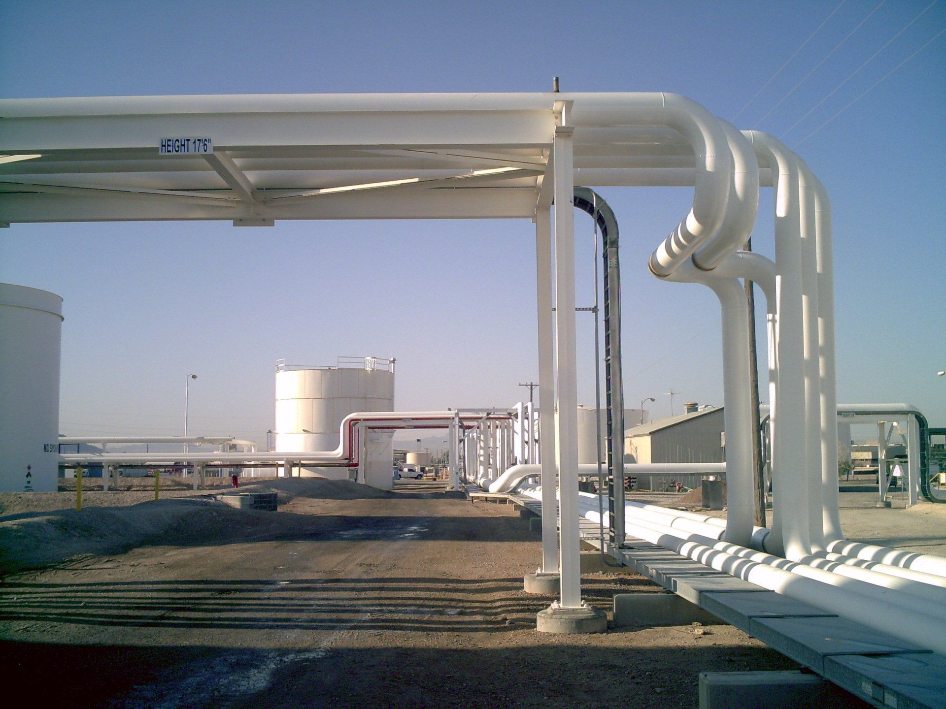 A row of white pipes are lined up under a canopy with a blue sky in the background