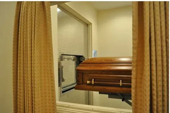 A coffin is sitting in a room behind a curtain