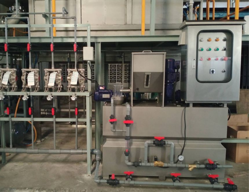 Industrial water treatment system with tanks, pipes, valves, and a control panel in a factory setting