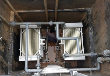 Two radiator units and metal pipes in a service pit, with a worker crouched between them