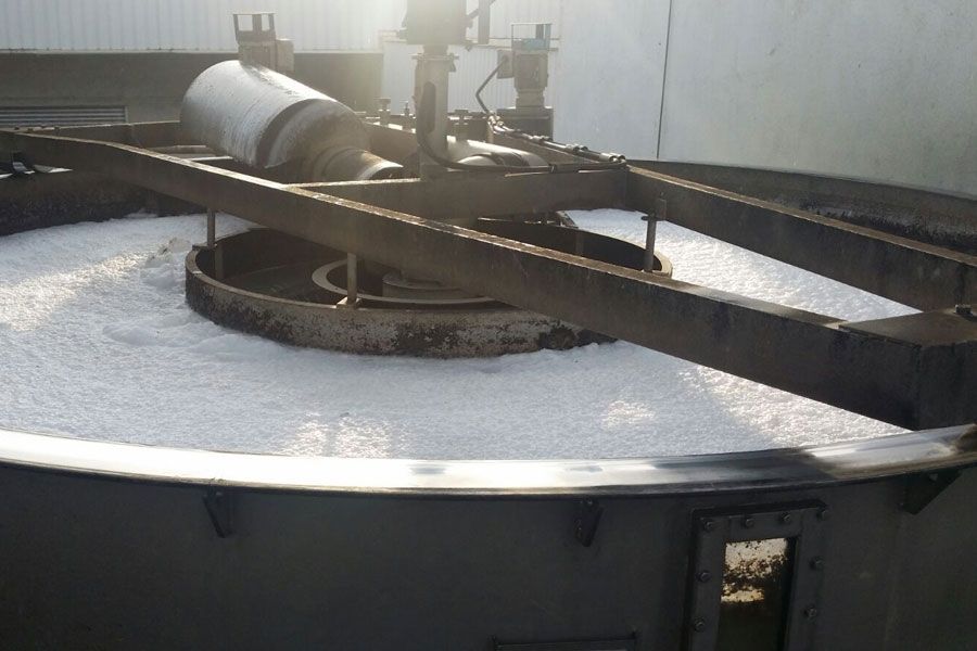 Large industrial tank with a metal lid and pipes, frosted white on top in bright sunlight