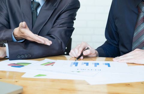 Two businesspeople reviewing colorful charts and graphs at a desk