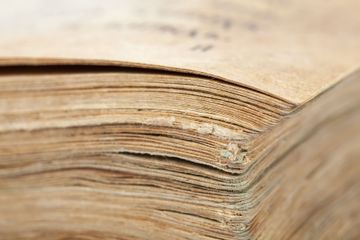Close-up of the worn pages of an old, yellowed book with frayed edges