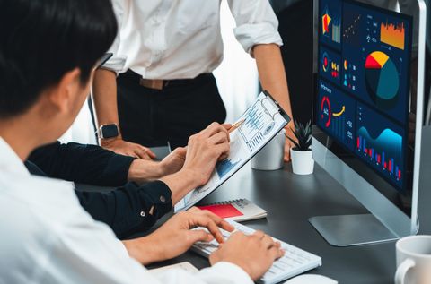 Team reviewing business charts on a desktop monitor in a meeting room