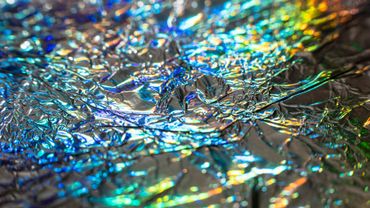 Abstract close-up of crinkled reflective foil with shimmering blue, gold, and silver highlights