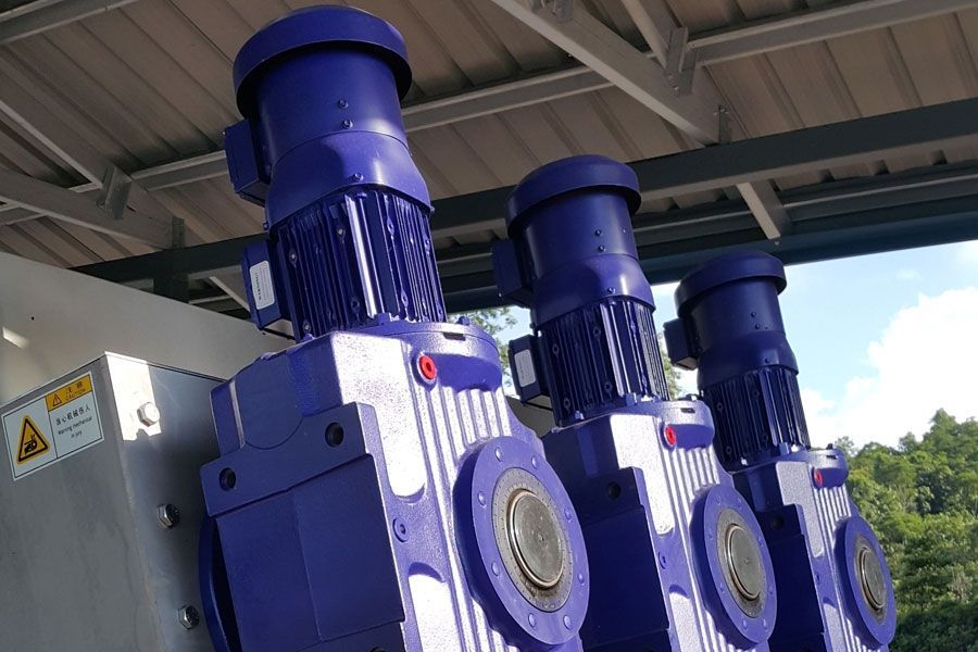 Blue industrial motors with gearboxes under a metal roof outdoors