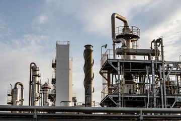 Industrial refinery with tall metal towers and pipes under a cloudy sky