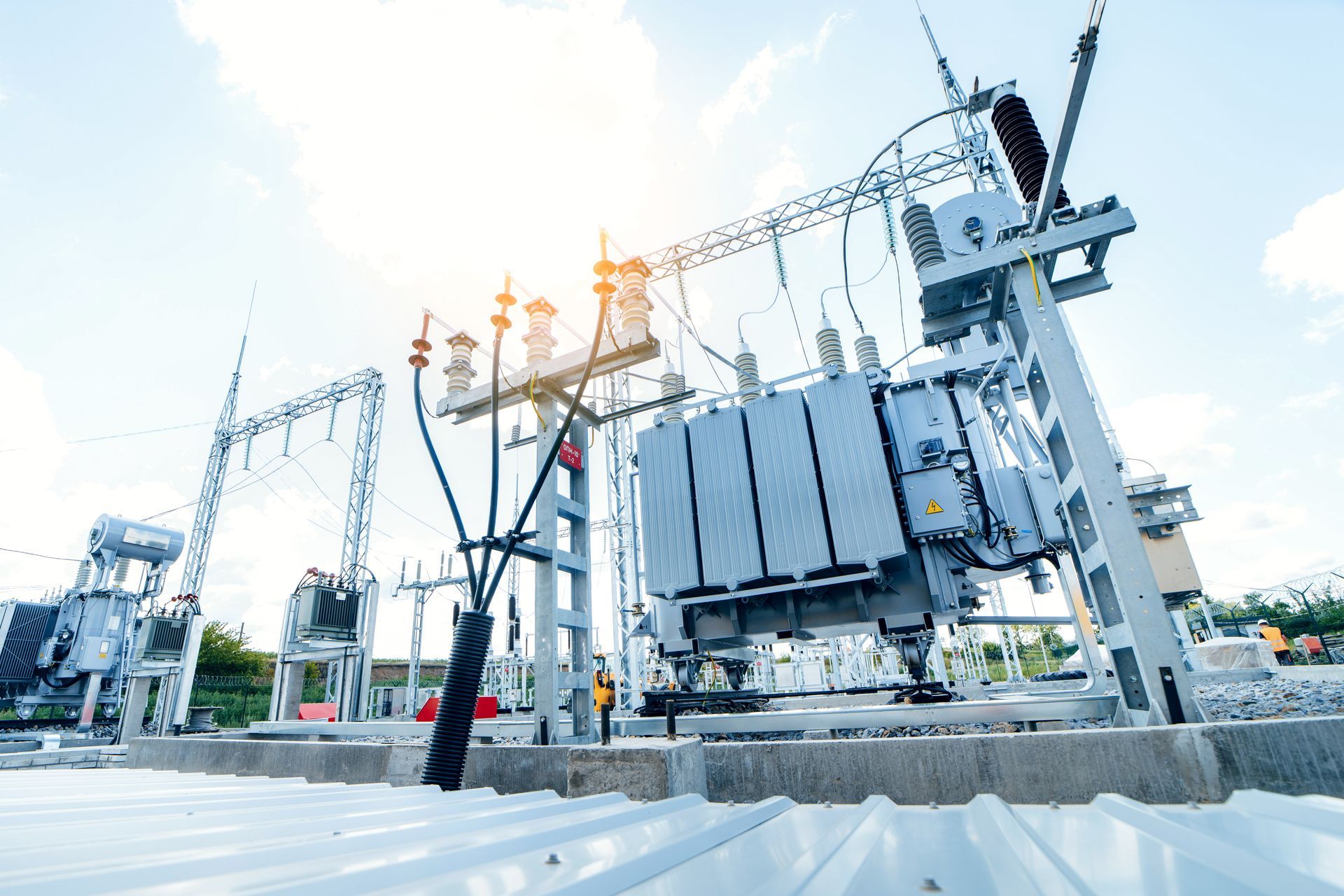 High-voltage electrical substation with transformers, power lines, and bright sunlight