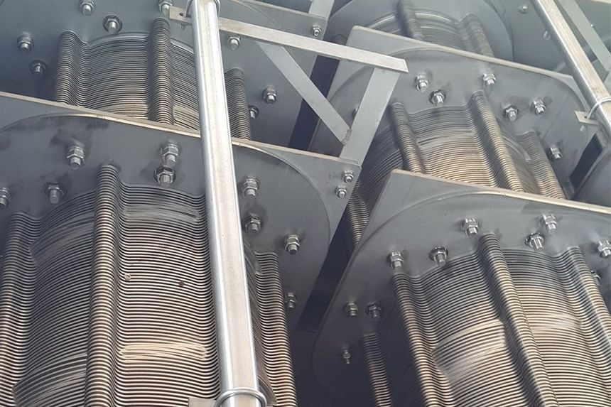 Close-up of industrial machinery with metal rollers, bolts, and a central silver shaft