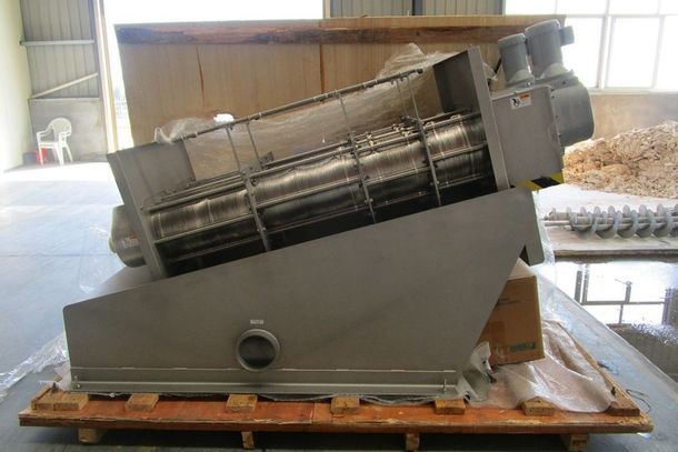 Large gray industrial machine on a wooden pallet in a warehouse, tilted on its side.