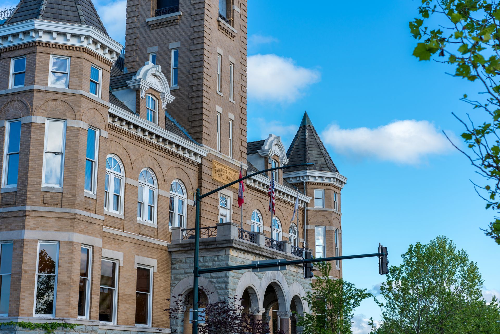 A large brick building with a clock tower and a traffic light in front of it.