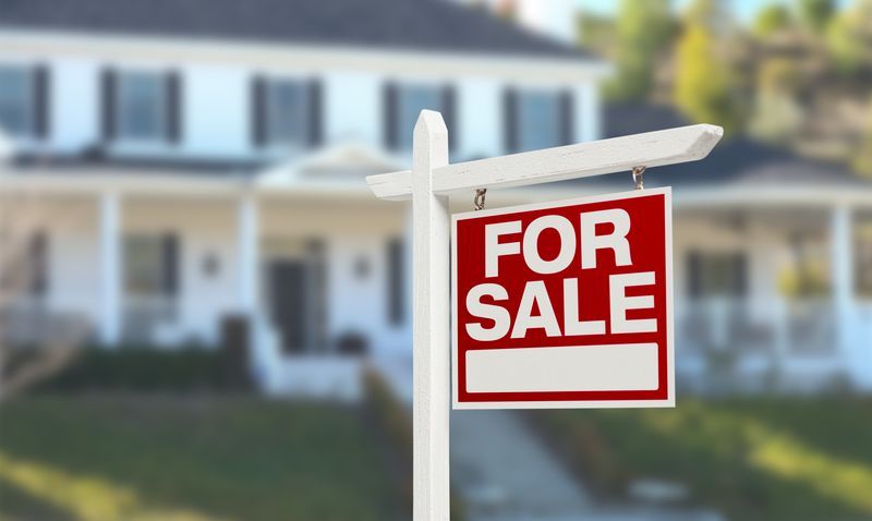 A for sale sign is in front of a house.
