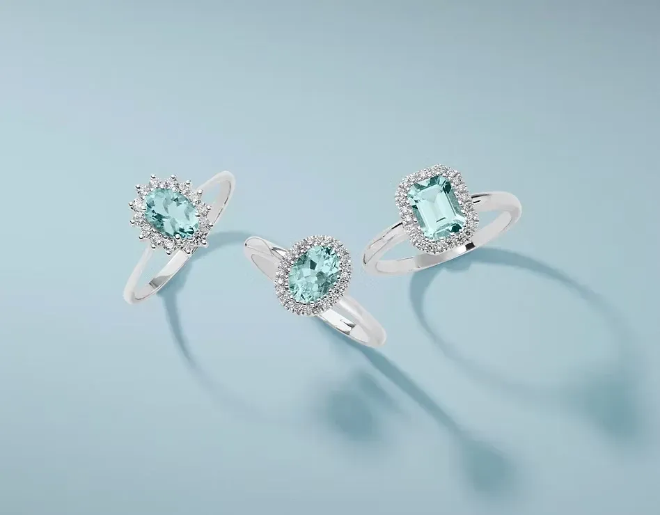 Tre anelli d’argento con pietre azzurre su uno sfondo azzurro chiaro
