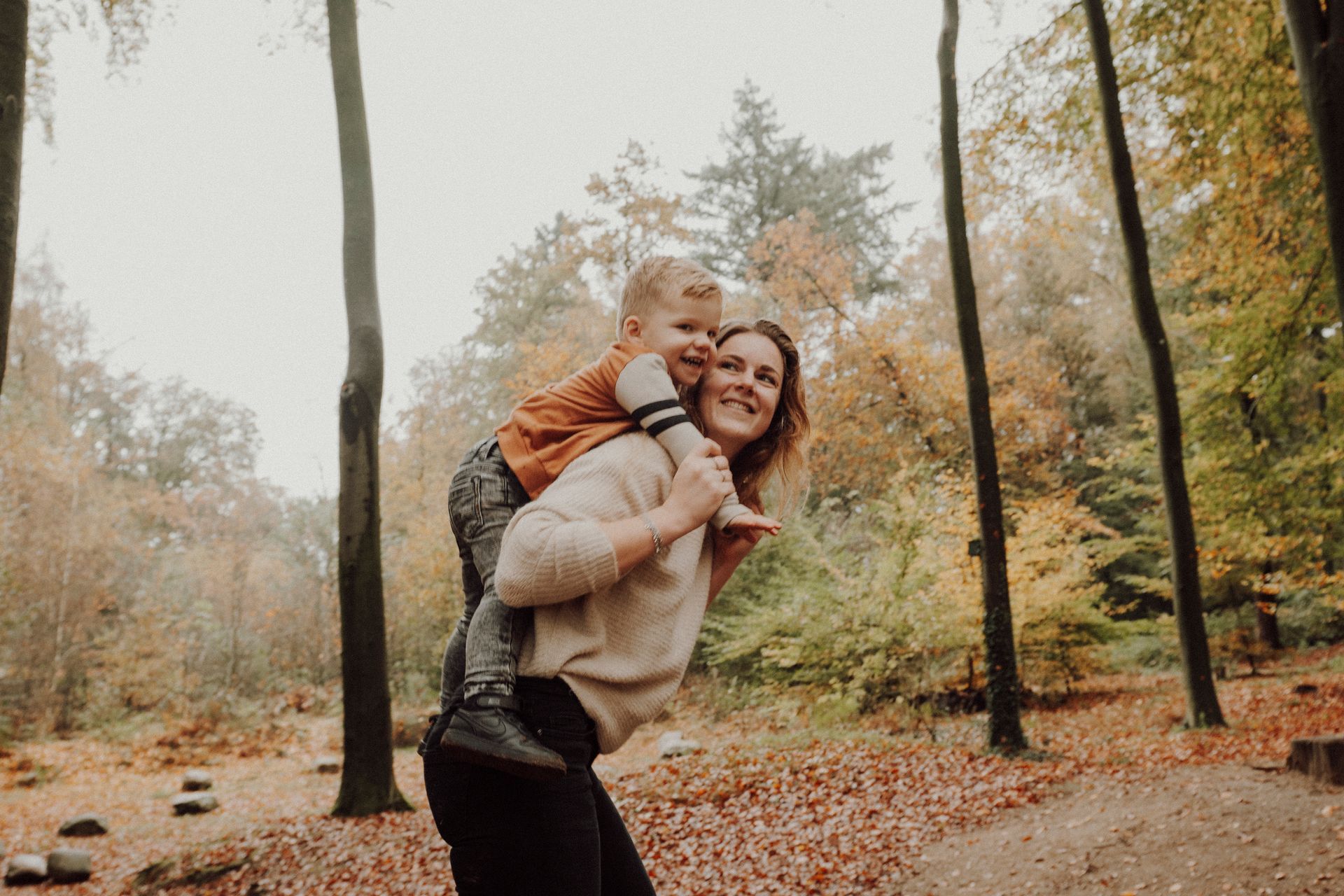 Een vrouw draagt ​​een kind op haar rug in het bos.