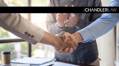 Two people in business attire shaking hands in an office setting