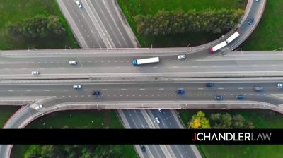 Aerial view of a highway interchange with cars and a white truck crossing over grass medians.