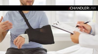 Patient with arm in sling speaking to doctor during medical consultation