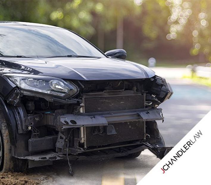 Black car with a damaged front end parked on a street