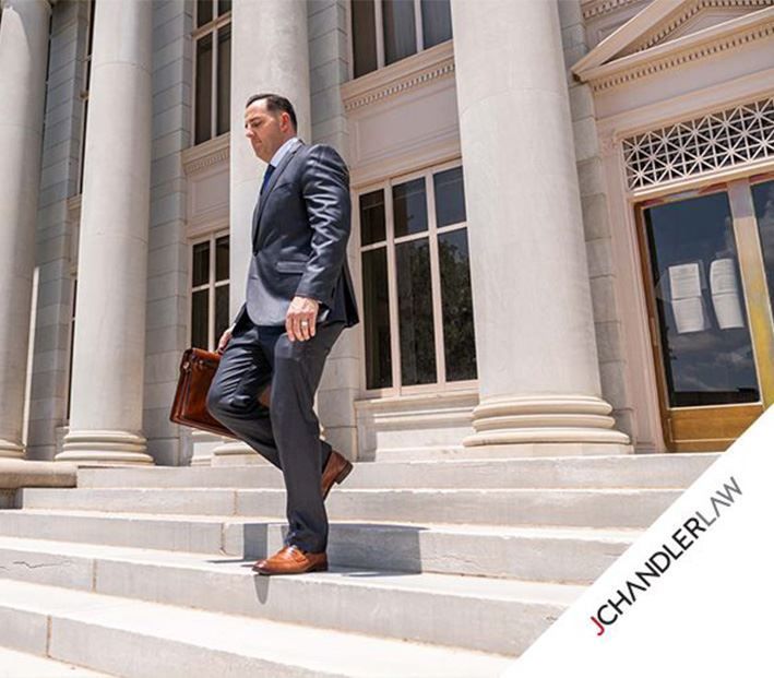 Man in dark suit walking down courthouse steps with a briefcase