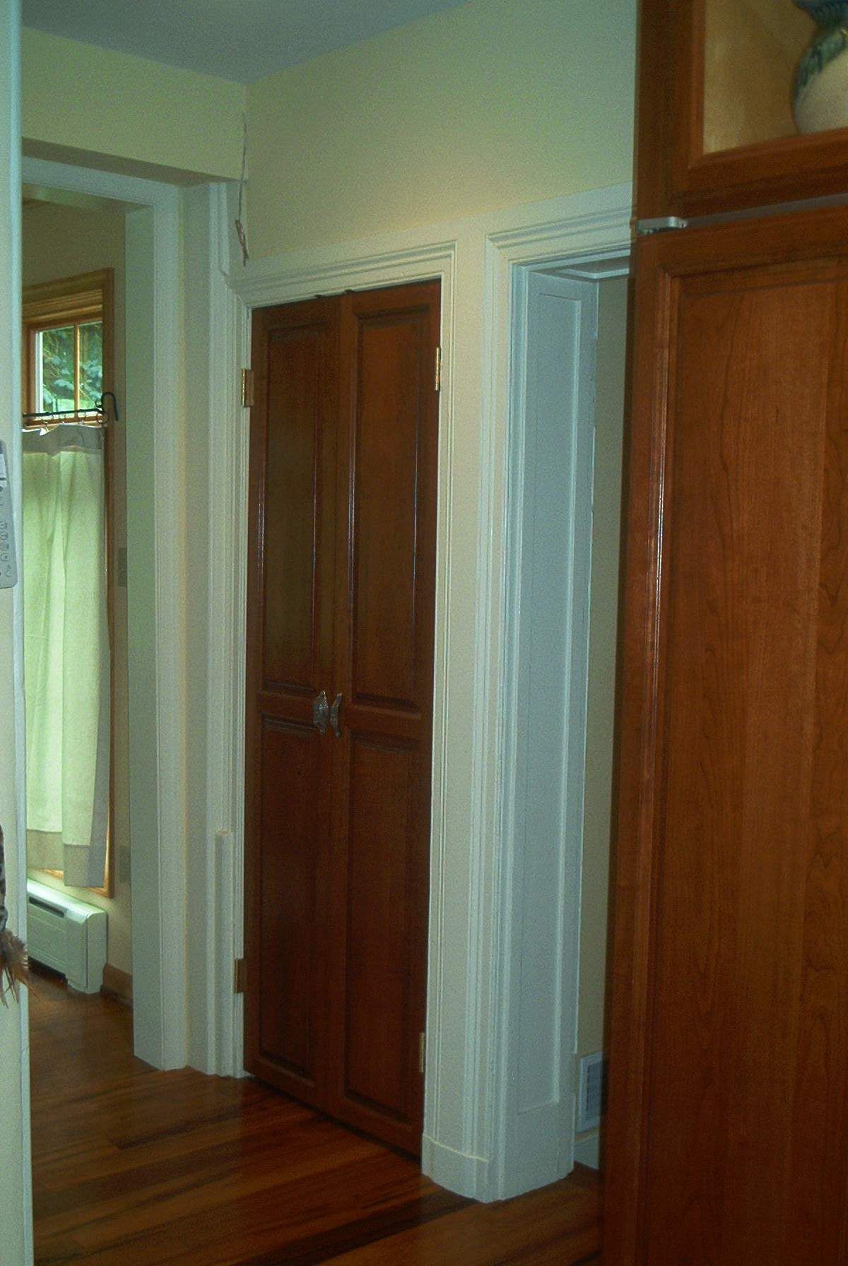 A hallway in a house with wooden doors and a window