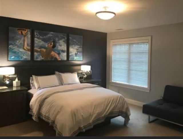 A bedroom with a bed a chair and a window