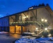 A large house with a balcony and stairs is lit up at night.