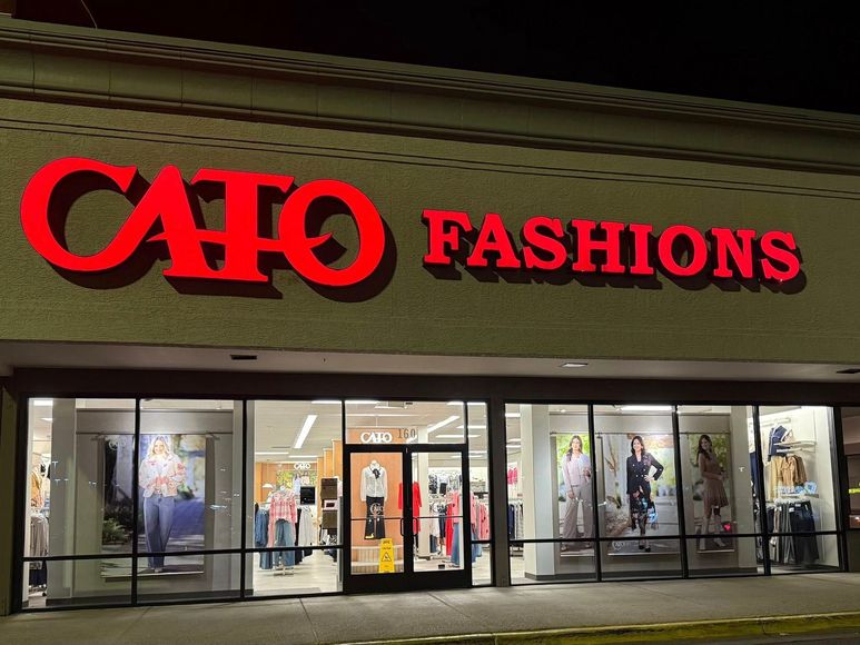 CATO Fashions storefront at night with bright red sign and window displays