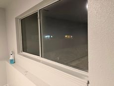 Empty room with large window at night and a bottle on the windowsill