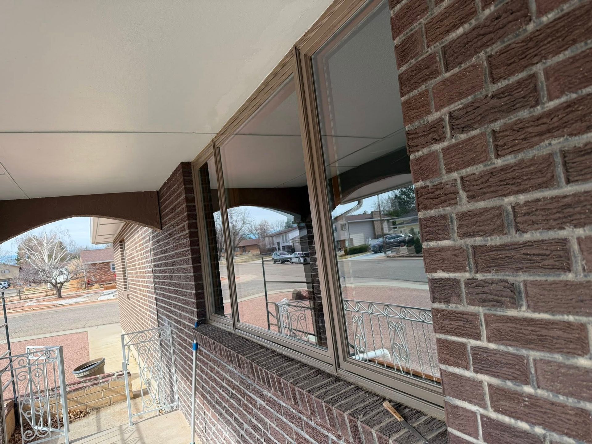Brick apartment balcony with windows overlooking a street and trees