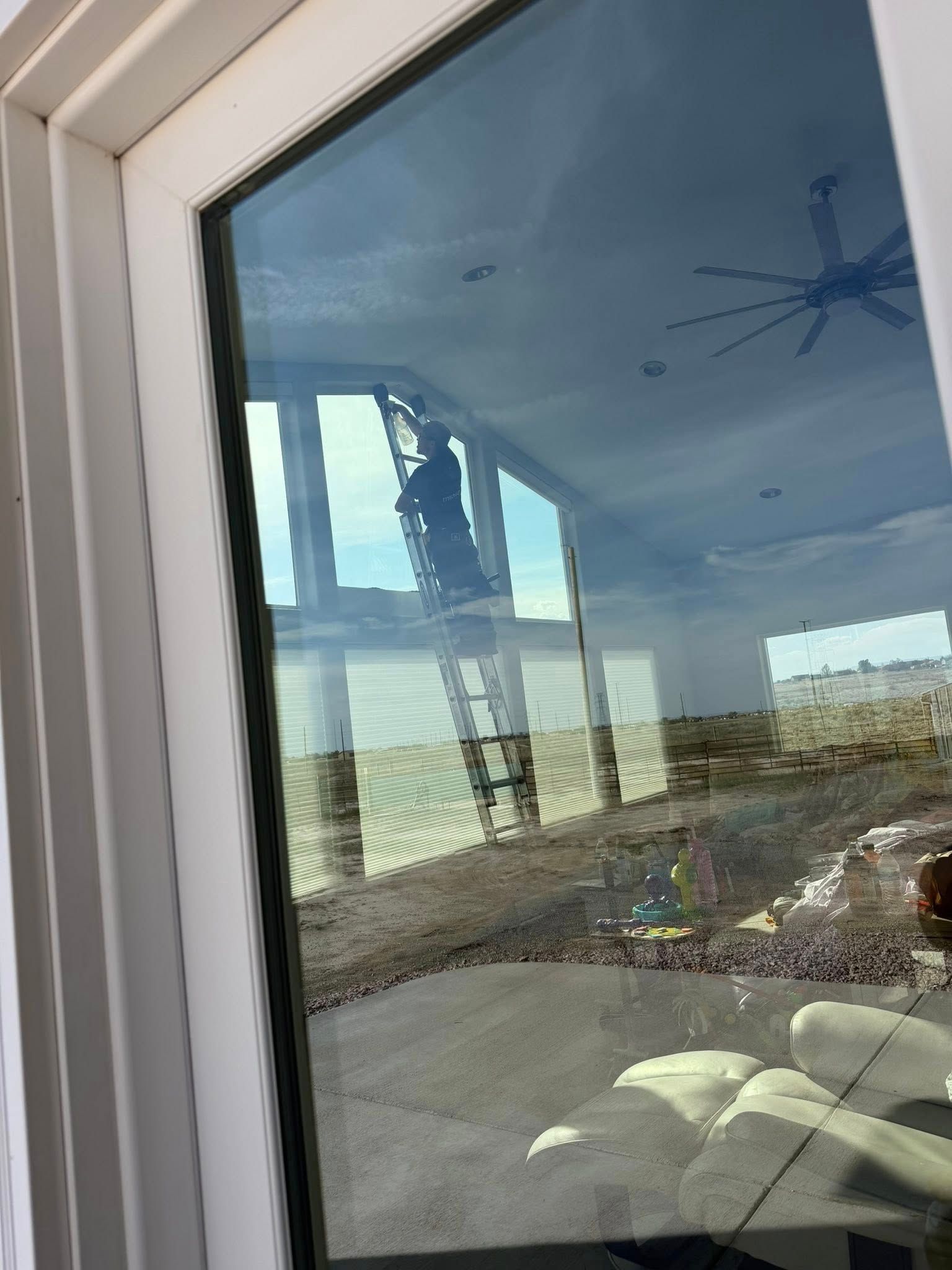 View through a window of a road and desert landscape, with bright sky reflections on the glass.