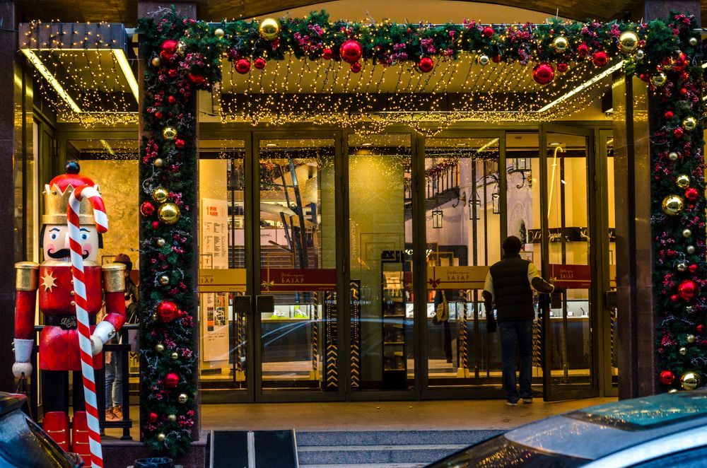 Festive storefront entrance decorated with Christmas lights, garlands, and a large nutcracker statue
