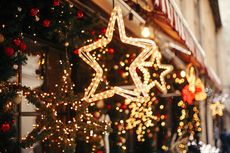 Glowing star-shaped holiday lights hanging outside a decorated storefront at night