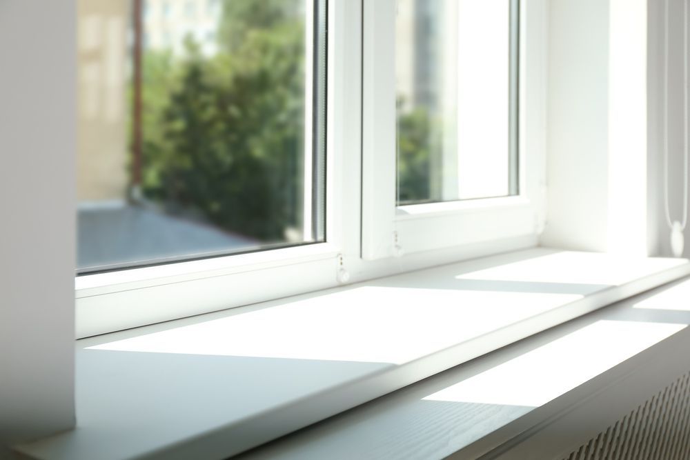 Sunlit white windowsill beside a bright window with soft shadows on the ledge