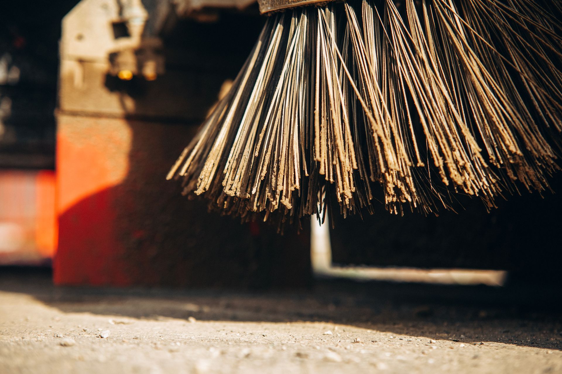 Close-up of mechanical sweeper brush bristles on pavement. Close-up of mechanical sweeper brush bristles on pavement.