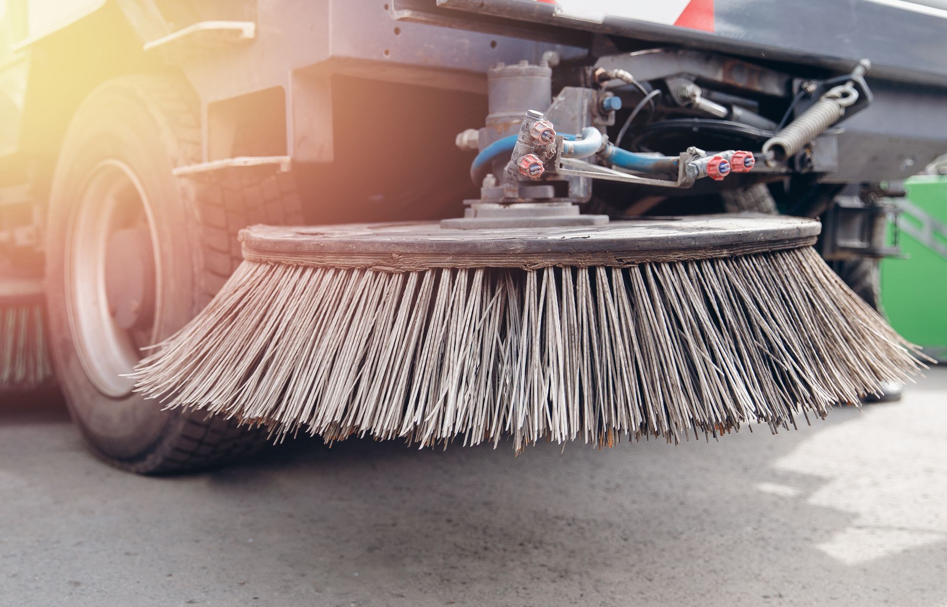 Close-up of a street sweeper brush mounted beneath a road-cleaning vehicle. Close-up of a street sweeper brush mounted beneath a road-cleaning vehicle.