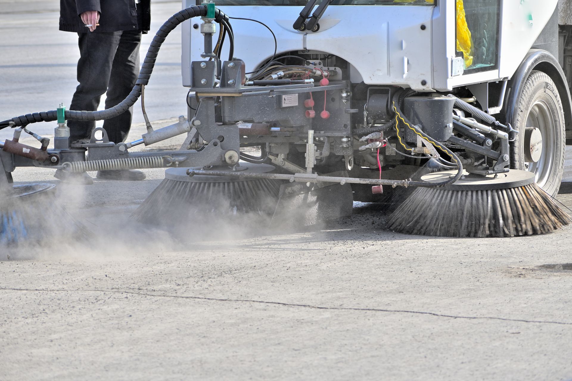 Street sweeping machine's rotating brushes removing debris from pavement