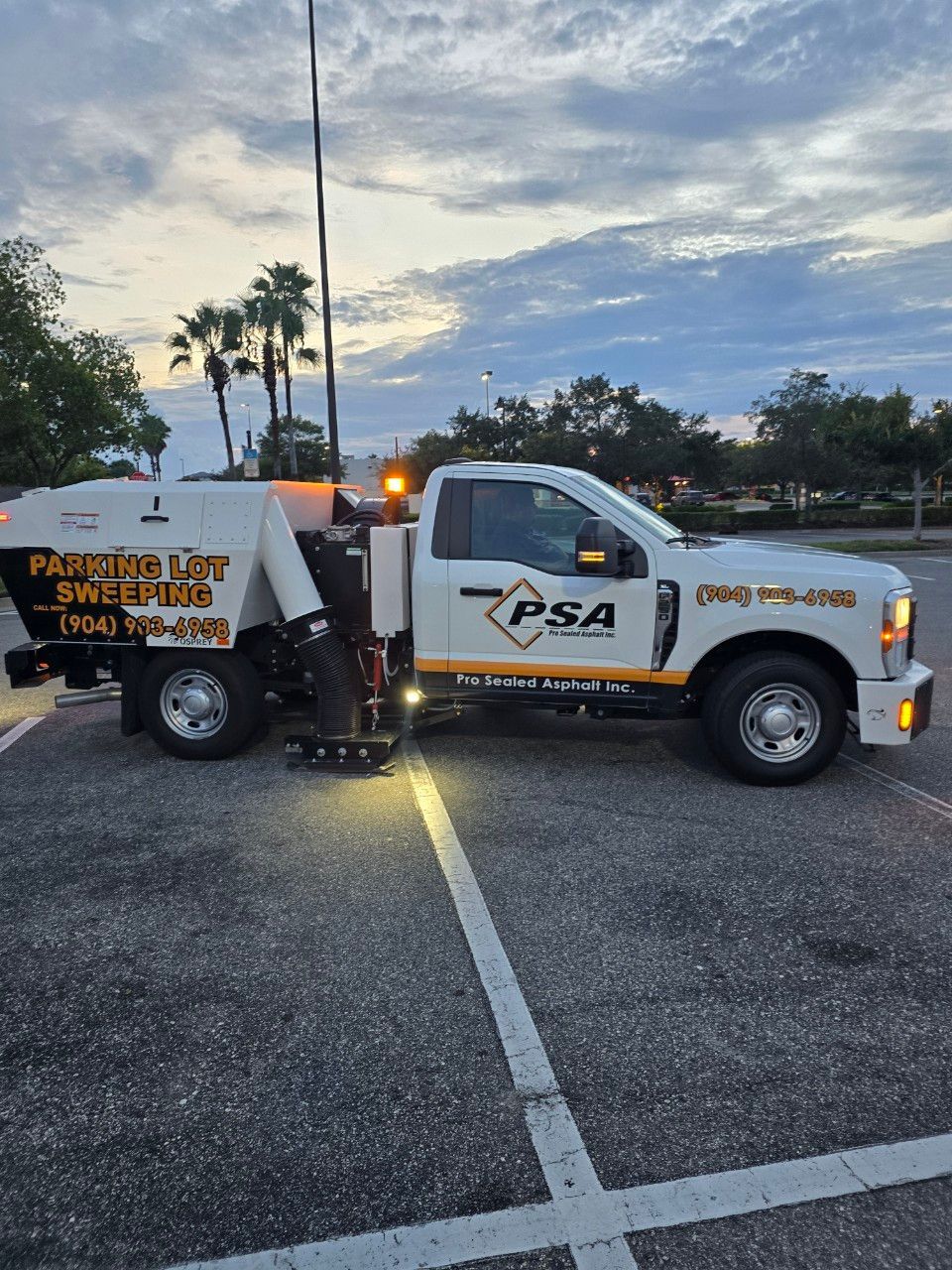 PSA utility truck parked on a road at dusk with an amber warning light and work sign on the side