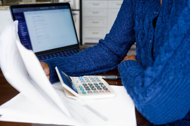 A woman is sitting at a table with a laptop and a calculator. A woman is sitting at a table with a laptop and a calculator.