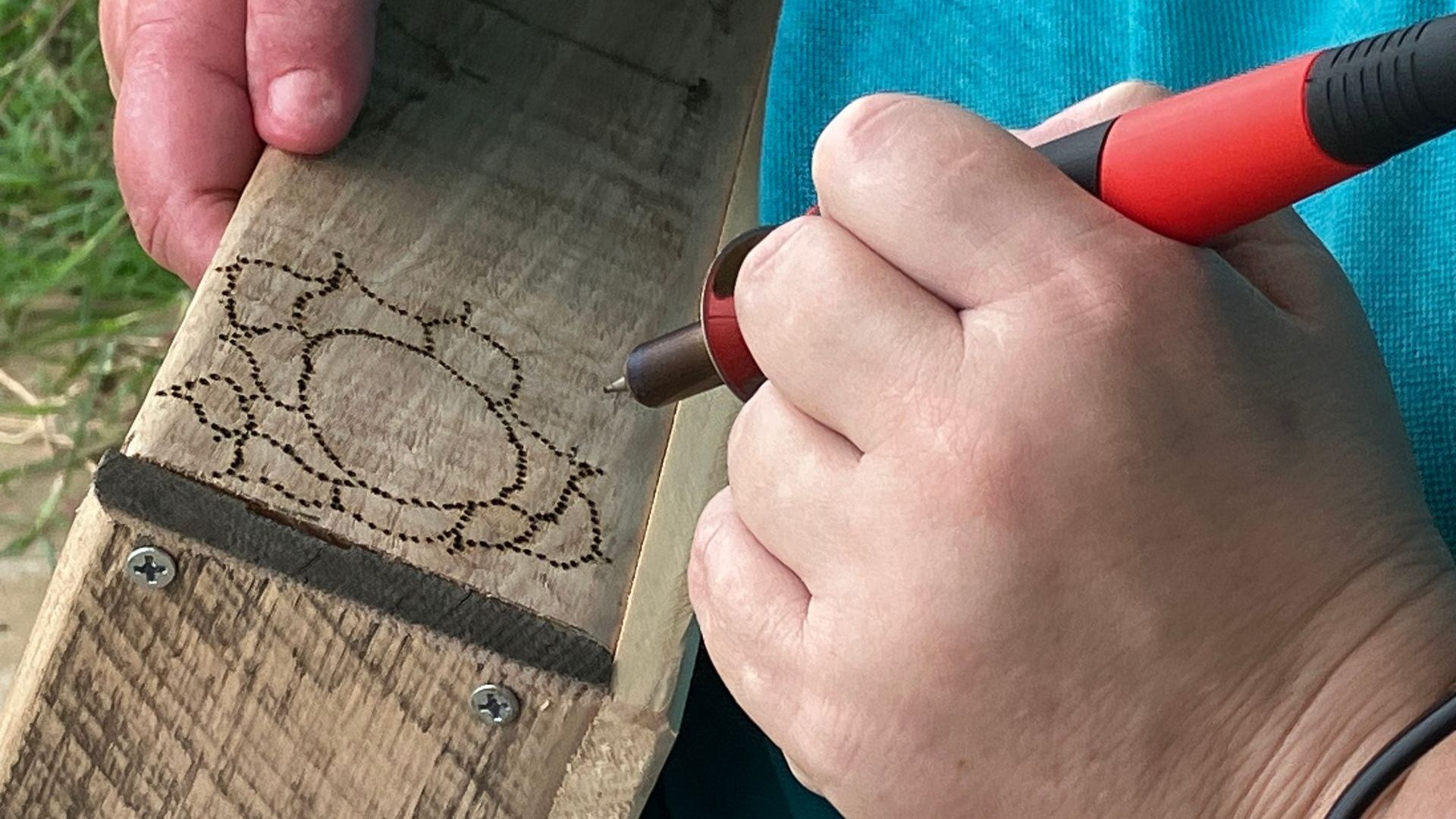 Client working with pyrography woodburning drawing on timber box